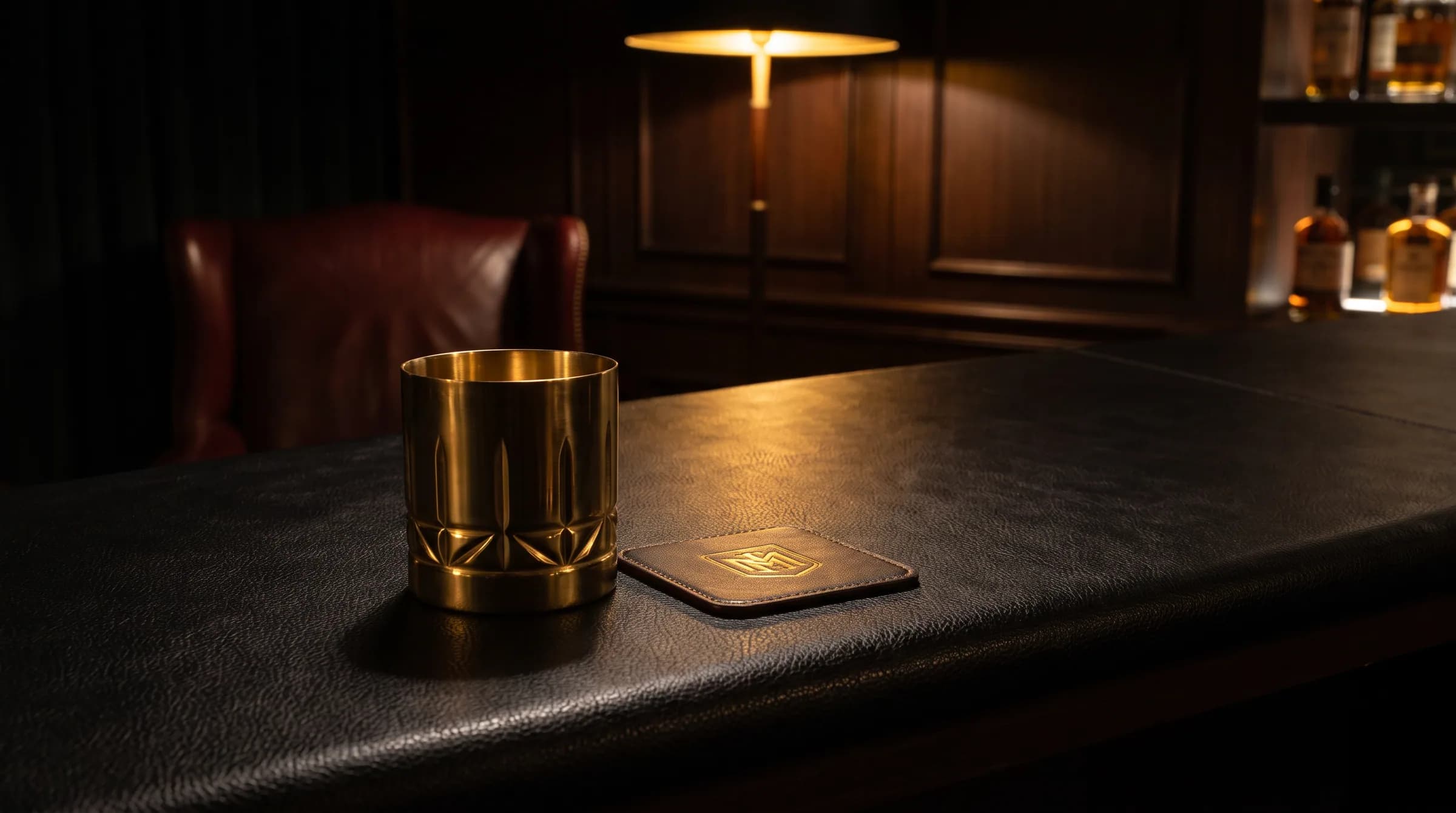 A brass tumbler on a coaster at the end of a dark bar