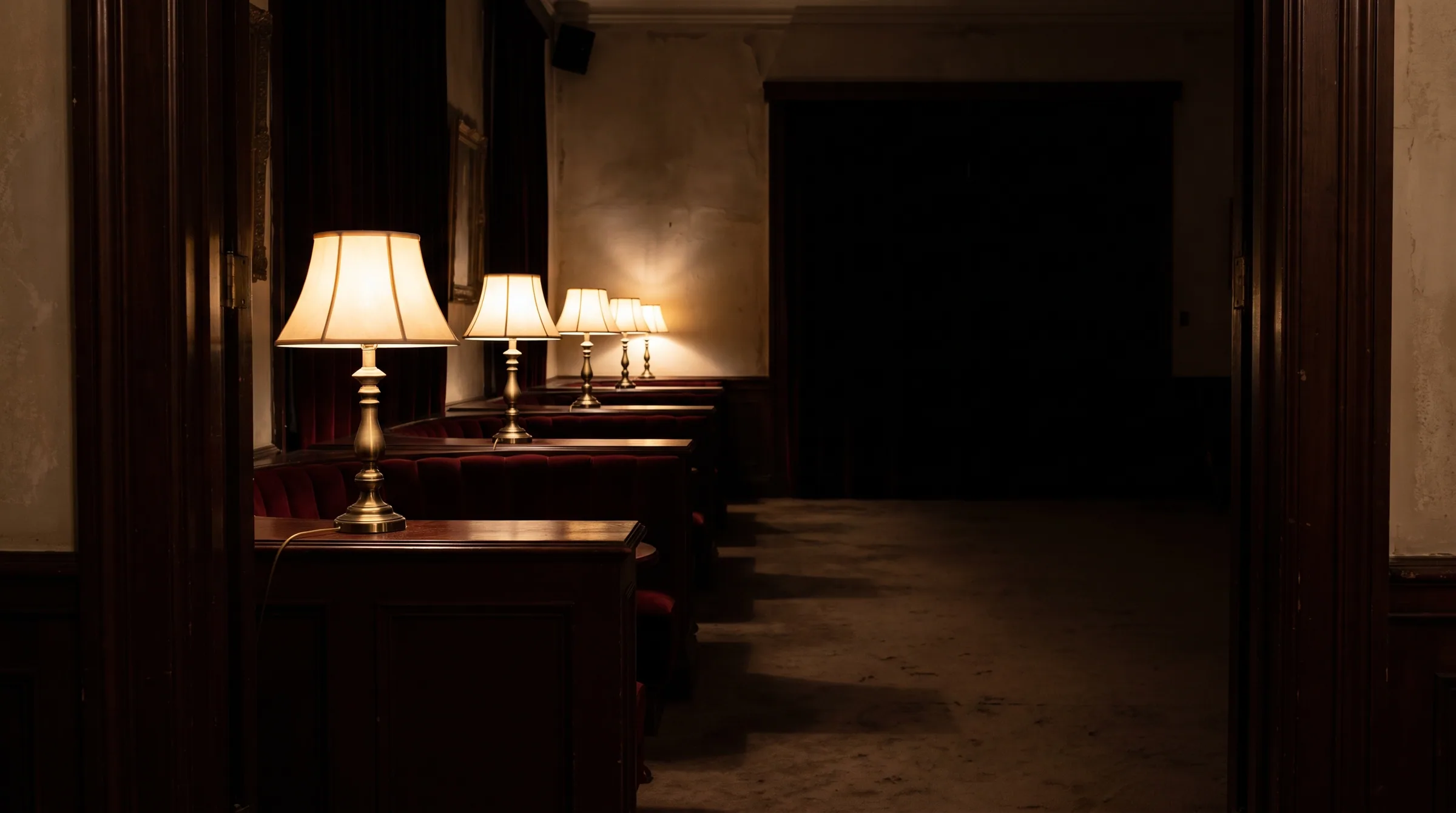 A row of brass lamps down a dark corridor of booths