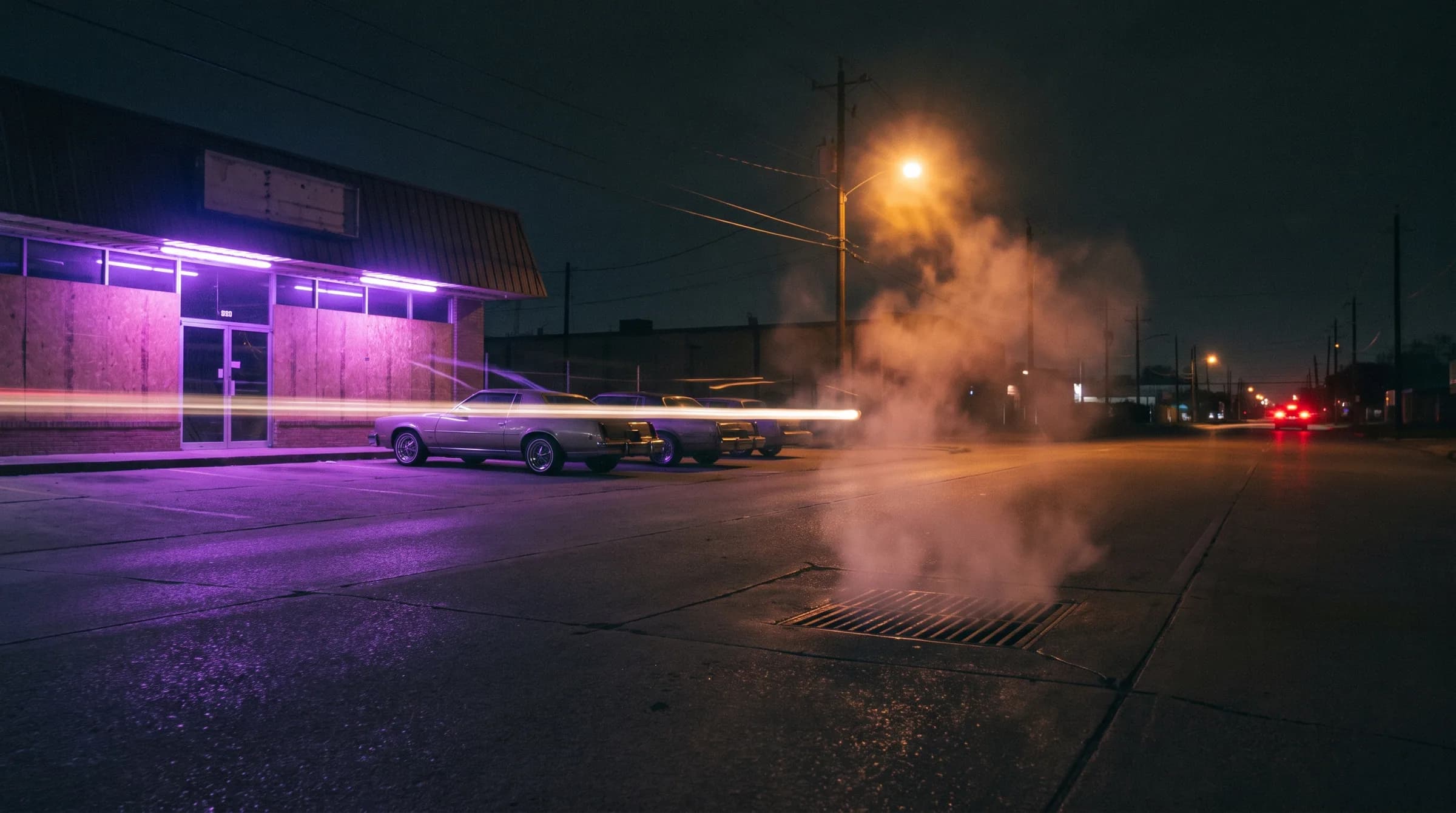 An empty street at night, purple neon on a shuttered storefront, steam off a grate
